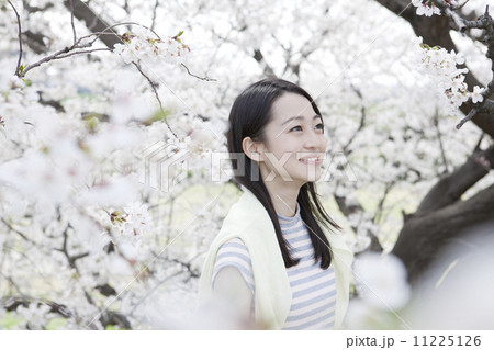 桜を背景に笑顔の若い女性 11225126