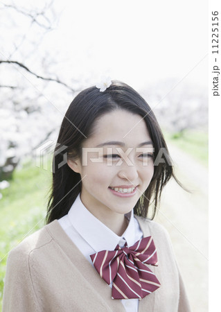 桜を背景に笑顔の女子高生 11225156