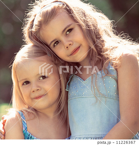 Outdoor portrait of two embracing cute little girls 11226367