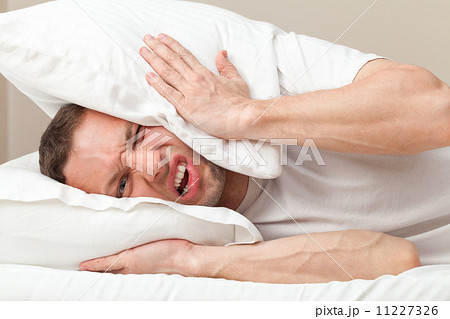Portrait of Young Caucasian man in bed angry about noise 11227326