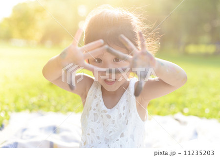 Little girls in causal showing off crayon marks on her hands in a park Little girls in causal showing off crayon marks on her hands in a park 11235203