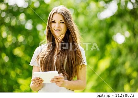 Beautiful young girl using a tablet in a park Beautiful young girl using a tablet in a park 11238672
