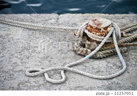Old rusted mooring bollard with knotted nautical ropes 11257051