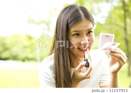 Beautiful girl doing makeup in park Beautiful girl doing makeup in park 11257953