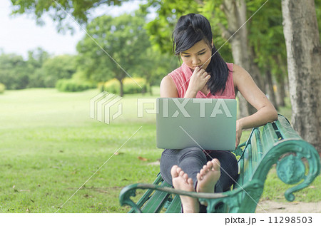 Beautiful young woman using laptop computer on a bench in the pa Beautiful young woman using laptop computer on a bench in the pa 11298503
