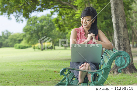Beautiful young woman using laptop computer on a bench in the pa Beautiful young woman using laptop computer on a bench in the pa 11298519
