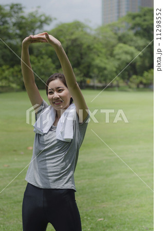 sporty girl warming up stretch her legs in the park 11298552