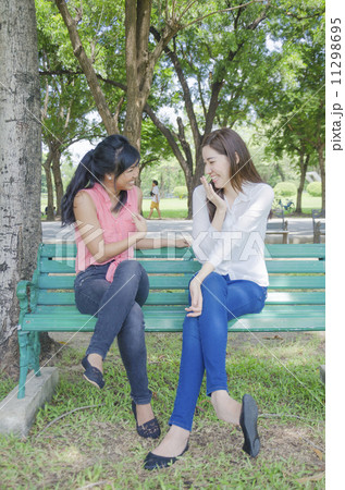 Two young beautiful Asian women talking about something at summe Two young beautiful Asian women talking about something at summe 11298695