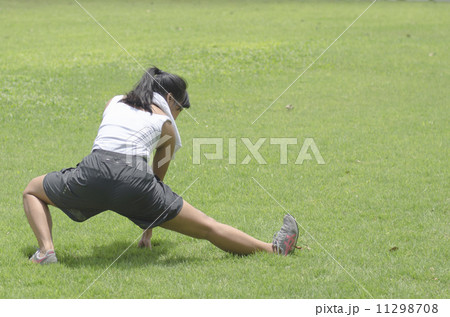 sporty girl warming up stretch her legs in the park 11298708