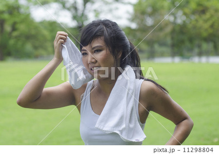 Asian woman wiping sweat with a towel after exercising Asian woman wiping sweat with a towel after exercising 11298804