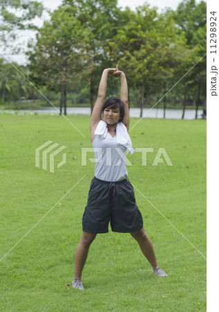 sporty girl warming up stretch her legs in the park 11298924