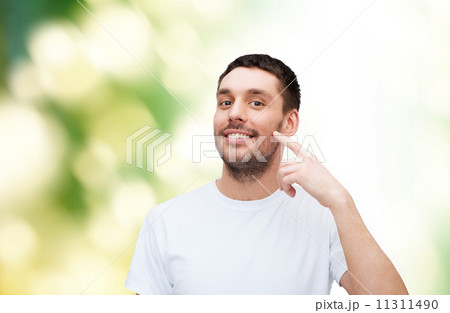smiling young handsome man pointing to cheek smiling young handsome man pointing to cheek 11311490