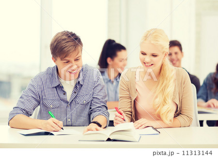 two teenagers with notebooks and book at school two teenagers with notebooks and book at school 11313144