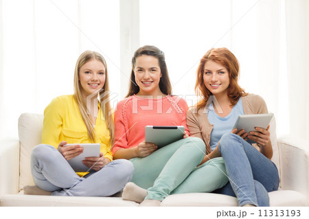 three smiling teenage girls with tablet pc at home three smiling teenage girls with tablet pc at home 11313193