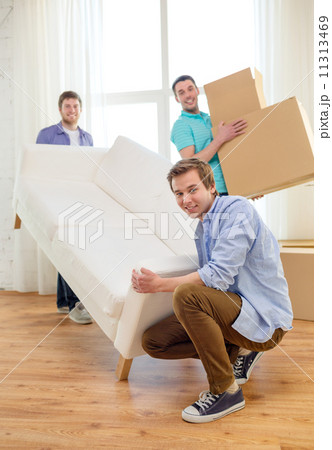 smiling friends with sofa and boxes at new home smiling friends with sofa and boxes at new home 11313469