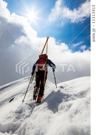 Ski mountaineer walking up along a steep snowy ridge with the s 11313915