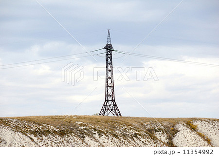 High voltage line and electricity pylon on coastline of river. 11354992