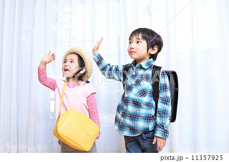 手を振る小学生と幼稚園児の写真素材