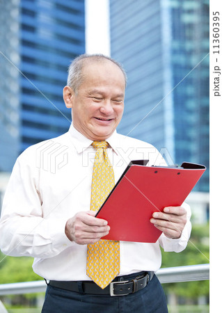 Senior business executive looking at red file 11360395