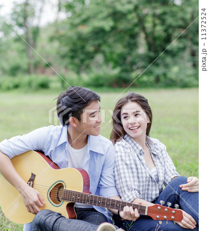 Young man playing guitar with his girlfriend Young man playing guitar with his girlfriend 11372524