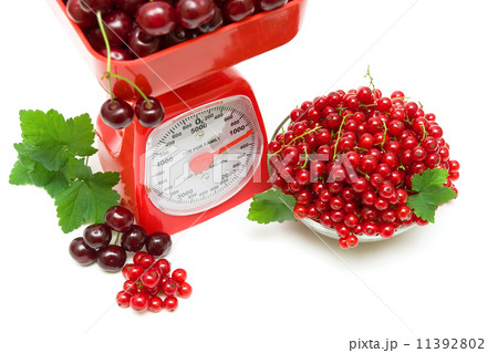 red currant berries, cherries and kitchen scale on white backgro 11392802