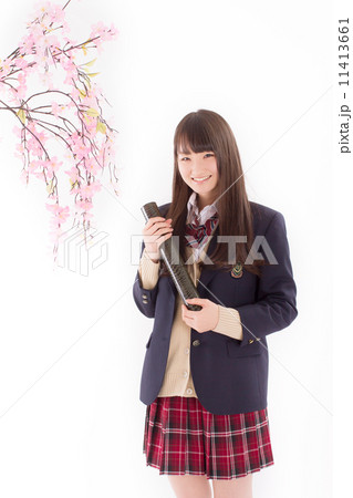 桜の木の横で卒業証書を手に持つ女子校生の写真素材