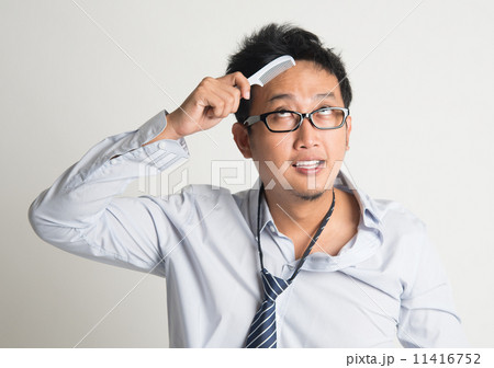Asian businessman combing hair Asian businessman combing hair 11416752