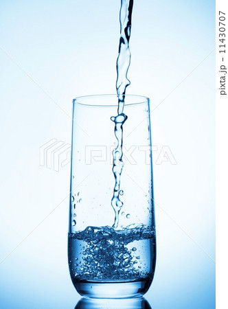 water pouring into glass on blue background 11430707