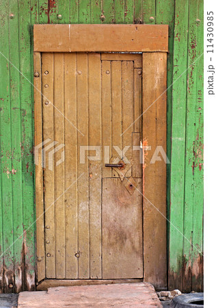 Old rural wooden door in grunge green fence 11430985