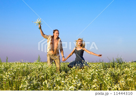 The happy young pair in the field of chamomiles jumps The happy young pair in the field of chamomiles jumps 11444310