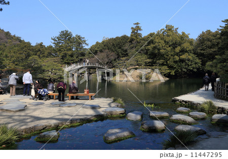 「栗林公園」吹上からの水が南湖に注ぐ吹上亭周辺は観光客がよく足を止めるところ。（左手前は吹上亭の縁台、そのむこうに偃月橋） 11447295