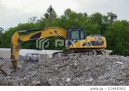 Yellow excavator at demolition on mountain of debris, view from the side 11448362