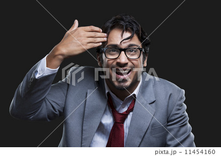 Irritated young businessman gesturing against black background Irritated young businessman gesturing against black background 11454160