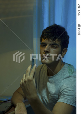 Portrait of male drug addict holding syringe at home Portrait of male drug addict holding syringe at home 11454162