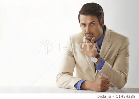 Portrait of young male entrepreneur sitting at office desk 11454238
