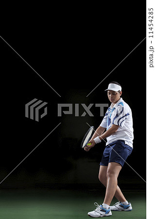 Female tennis player preparing to serve isolated over black background 11454285