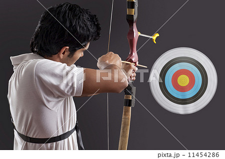 Young man aiming target with bow against black background 11454286