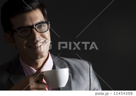 Happy businessman with coffee cup against black background 11454309