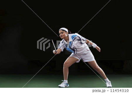 Young woman in sportswear playing badminton over black background 11454310