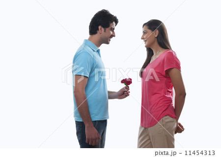 Happy young man giving rose to woman against white background 11454313