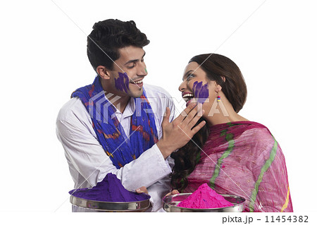 Man applying holi colour on womans face 11454382