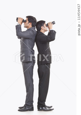 Full length of businessmen looking through binoculars against white background 11454437