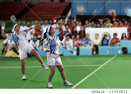 Young female players playing doubles with spectators in the background Young female players playing doubles with spectators in the background 11454651