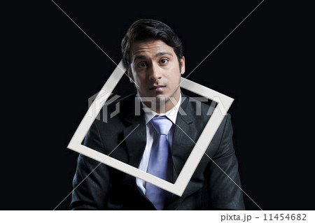 Portrait of worried businessman with frame hanging in neck against black background Portrait of worried businessman with frame hanging in neck against black background 11454682