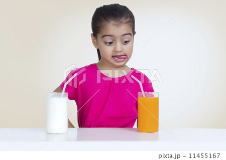 Confused girl choosing between juice and milk against colored background 11455167