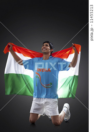 Hockey player looking up as he holds Indian flag with pride against black background 11455213