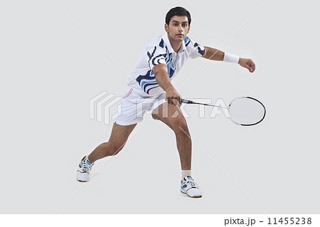 Young man playing badminton isolated over gray background 11455238