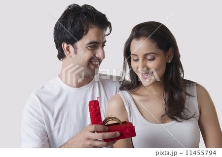 Happy man gifting bangles to woman against white background 11455794