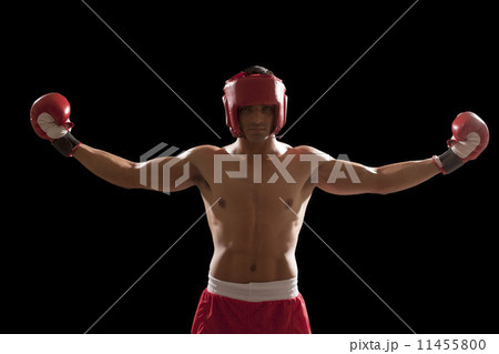 Portrait of confident male boxer standing with arms outstretched isolated over black background 11455800
