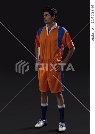 Soccer player standing with hands on hip as he looks away isolated over black background Soccer player standing with hands on hip as he looks away isolated over black background 11455844